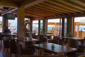 a restaurant with tables and chairs and windows at Socrates Hotel in Sidari