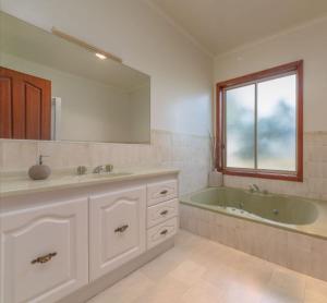a bathroom with a tub and a sink and a mirror at Beltie Park Homestead in Wangaratta +6 photos