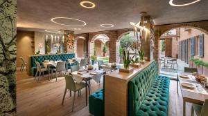 um restaurante com cabinas verdes, mesas e cadeiras em Il Cortile di San Michele em Guarene