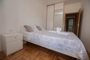 Schlafzimmer mit einem weißen Bett und einem Spiegel in der Unterkunft Cozy Apartment SINN in Trebinje