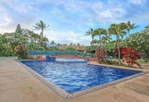 a large blue pool with palm trees in a yard at KOA 3L in Kihei