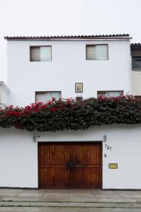 ein weißes Gebäude mit einer Holztür und roten Blumen in der Unterkunft Jose Luis Hostal Boutique in Lima
