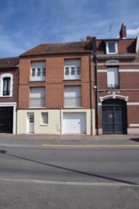 een bakstenen gebouw met twee garagedeuren in een straat bij Beau Studio Cambrai CENTRE VILLE in Cambrai