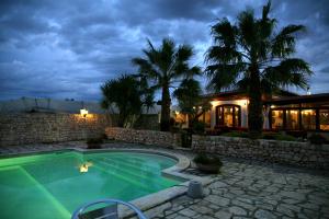 a swimming pool in front of a house with palm trees at Dal Canonico in Mola di Bari