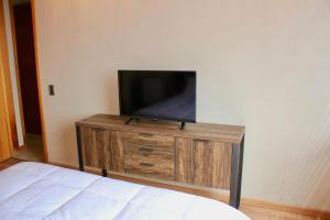 a flat screen tv sitting on top of a wooden dresser at Departamento Jardines de Huayquique in Iquique