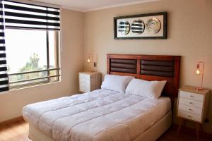 a bedroom with a large bed and a window at Departamento Jardines de Huayquique in Iquique