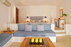 a bedroom with a blue couch and a bed at Tamarix Del Mar Suites in Kamari