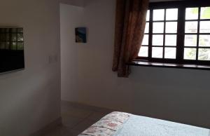 a bedroom with a bed and a window at Apartamentos de Férias por Temporada Martim De Sá in Caraguatatuba