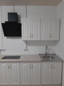 a kitchen with white cabinets and a sink at Жилье отдельное in Odesa