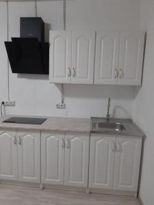 a kitchen with white cabinets and a sink at Жилье отдельное in Odesa