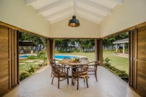 comedor con mesa y sillas y ventana grande en Nakatumble - Luxury Sustainable Villa with Farm, en Pangona