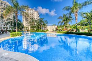 ein großer Swimmingpool mit Palmen und Gebäuden in der Unterkunft Jaco Bay 3702 in Jacó