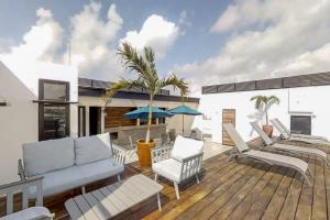 une terrasse avec des chaises longues et un palmier dans l'établissement Icono Playa Condos, B307, à Playa del Carmen