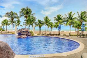 uma piscina com palmeiras e uma praia em Diamante del Sol 602N em Jacó