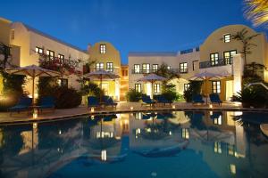 a hotel with a swimming pool at night at Tamarix Del Mar Suites in Kamari