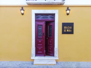 een geel gebouw met een paarse deur en een bord erop bij Casa Brazao Mira in Casa Branca