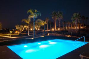 a swimming pool lit up at night with palm trees at La Marabulla in Ronda