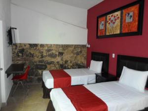 a hotel room with two beds and a desk at Hotel Montroi City in Colima