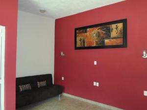 a living room with red walls and a black couch at Hotel Montroi City in Colima