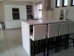 a kitchen with white cabinets and a island with white chairs at Villa Zen in Narbonne