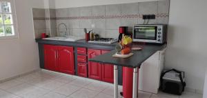 cocina con armarios rojos y microondas en Escale Caraibes, en Trois-Rivières