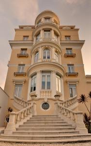 un bâtiment jaune avec des escaliers en face de celui-ci dans l'établissement Hotel Inglaterra - Charme & Boutique, à Estoril