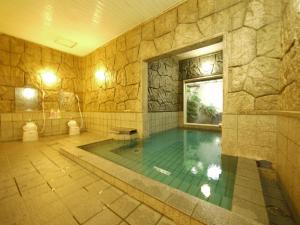 a large swimming pool with a stone wall at Hotel Route-Inn Court Ina in Ina