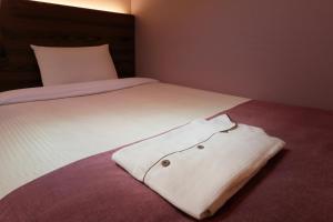 a white shirt is laying on a bed at Keio Presso Inn Ikebukuro in Tokyo +16 photos