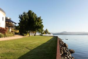a grassy lawn next to a lake with a house at Wrest Point in Hobart