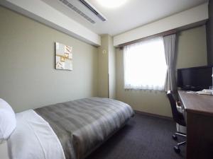a hotel room with a bed and a desk and a window at Hotel Route-Inn Myoko Arai in Myoko