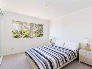 a white bedroom with a bed and two windows at Haven Waters 6 in Forster