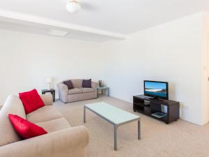 a living room with a couch and a tv and a table at Haven Waters 6 in Forster