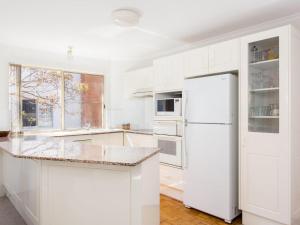 a kitchen with white cabinets and a white refrigerator at Haven Waters 6 in Forster