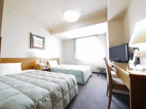 a hotel room with a bed and a desk with a computer at Hotel Route-Inn Igaueno -Igaichinomiya Inter- in Iga