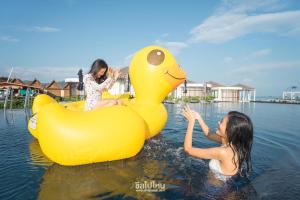 twee meisjes spelen op een gele rubberen eend in het water bij Kept Bangsaray Hotel Pattaya in Bang Sare