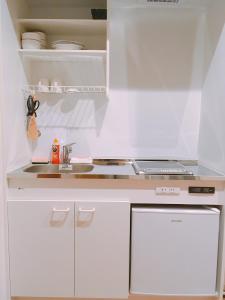 a kitchen with white cabinets and a laptop on the counter at TOKIHouse 京都時光 in Kyoto