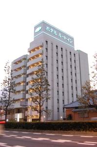 a tall white building with a sign on it at Hotel Route-Inn Tsu Ekiminami -Kokudo23gou- in Tsu
