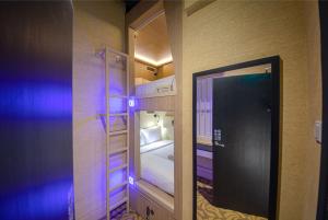 a small room with a bunk bed and a mirror at CUBE Boutique Capsule Hotel at Kampong Glam in Singapore