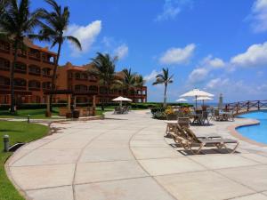 a walkway next to a resort with benches and a pool at Luxury Suites By Estrella del Mar in Mazatlán