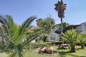 un jardín con palmeras, una mesa y un edificio en Malemi Organic Hotel en Skala Kallonis