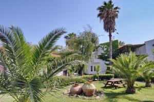 un giardino con palme, un tavolo e un edificio di Malemi Organic Hotel a Skala Kallonis