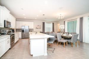 a kitchen with white cabinets and a table with chairs at 1719Cvt Orlando Newest Resort Community Home Villa in Orlando