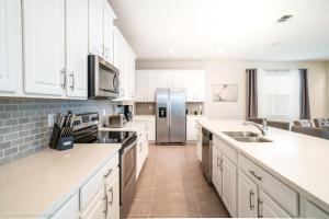 a kitchen with white cabinets and a stainless steel refrigerator at 1719Cvt Orlando Newest Resort Community Home Villa in Orlando