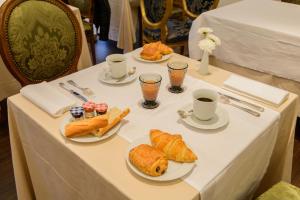 a table with three plates of bread and cups of coffee at The Originals Boutique, Hôtel Aultia, Ault in Ault