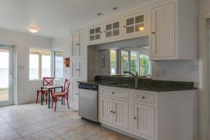 a kitchen with white cabinets and a table and chairs at Sunsetter on Sapphire Shores in Sarasota