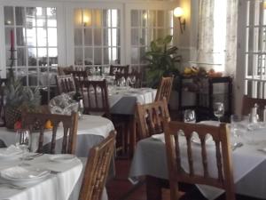 a restaurant with tables and chairs with white tablecloths at Hotel Beira Mar in Angra do Heroísmo