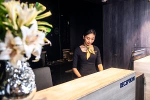 a woman is standing behind a counter with at CUBE Boutique Capsule Hotel at Chinatown in Singapore