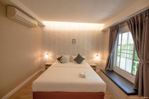 a bedroom with a bed and a window at Color Ville Hotel SHA Certified in Sakon Nakhon