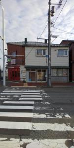 uma rua vazia com uma faixa de pedestres em frente a um edifício em Hakodate station 5minutes walk vacation stay em Hakodate