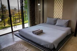 Ce lit se trouve dans un dortoir doté d'une grande fenêtre. dans l'établissement Phu Pha View Doi, à Samoeng